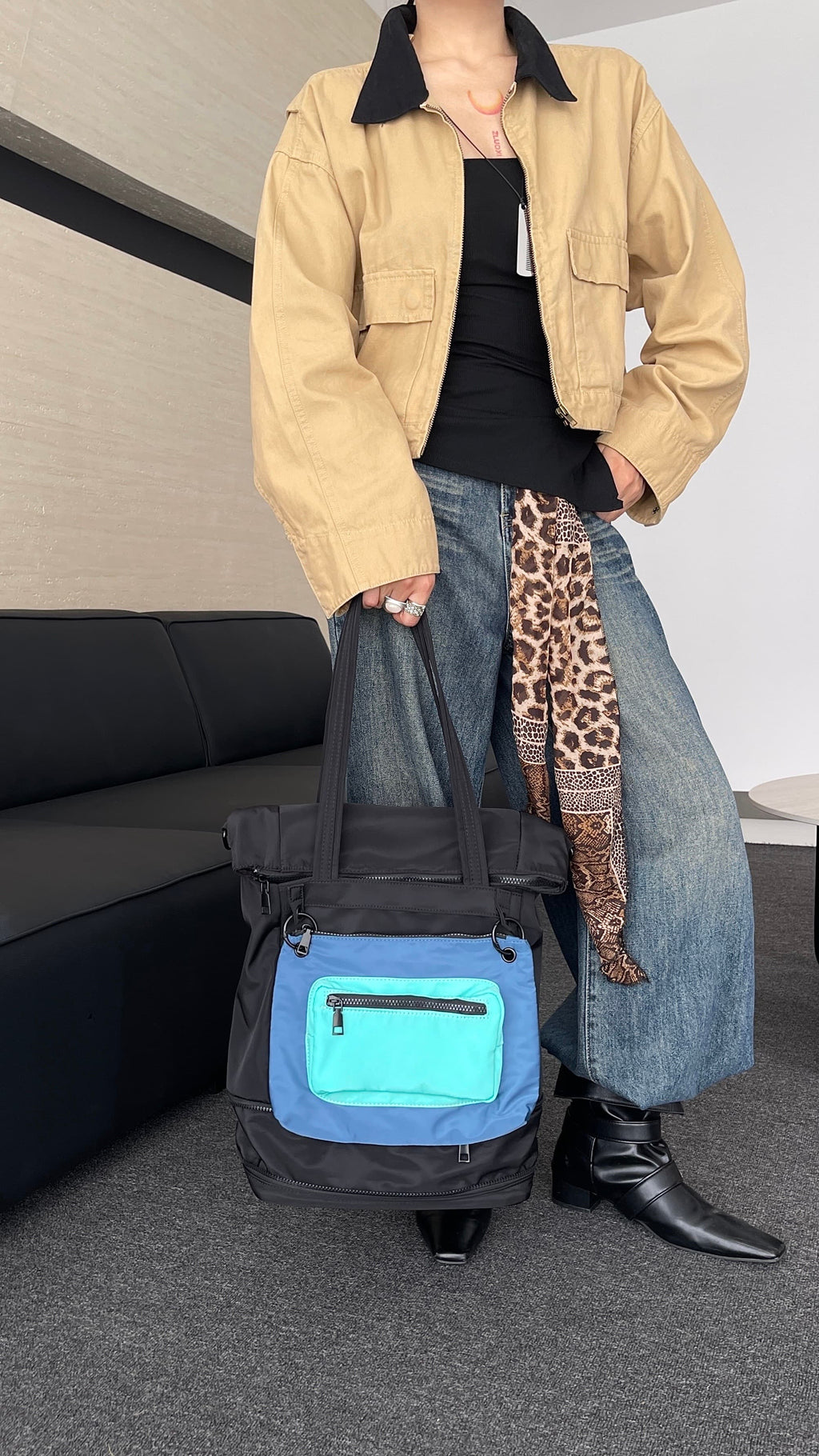 Person holding a black and blue bag with a leopard print item on a couch.