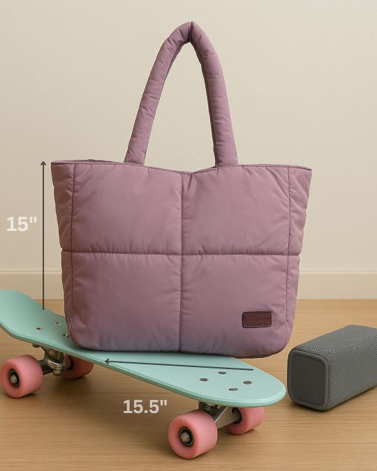 Purple quilted tote bag on a skateboard with measurements indicated, next to a gray speaker.Quilted puffer tote bag with padded handles and a soft structured silhouette – lightweight, stylish, and perfect for daily use, college, travel, or shopping. Designed for comfort and statement appeal, this spacious carryall from Tales of Totes is a trendy alternative to Zouk, Lavie, and DailyObjects in India’s fashion accessories market."