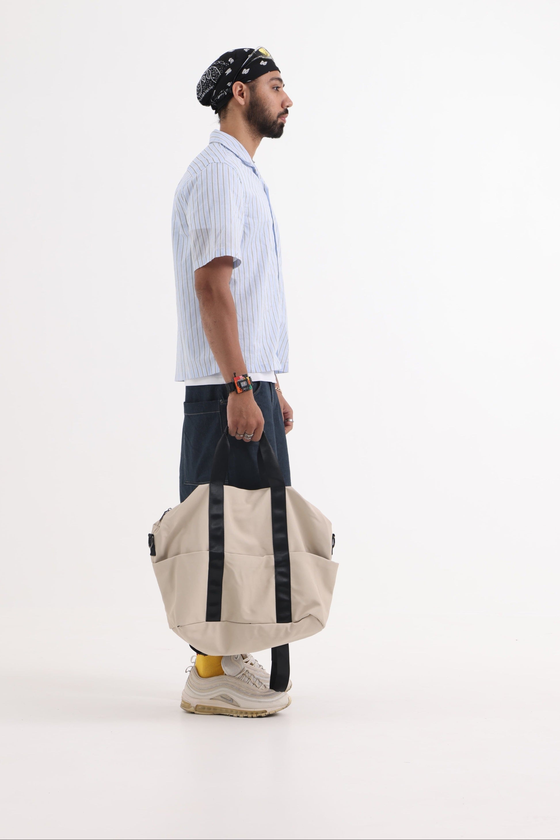 A unisex duffel tote bag with a sleek, minimal design featuring two vertical straps, dual carry handles, an adjustable shoulder strap, and side pockets. Spacious enough for travel or daily use, crafted from durable, water-resistant material with a zippered top closure. Ideal for college, gym, or casual outings.
