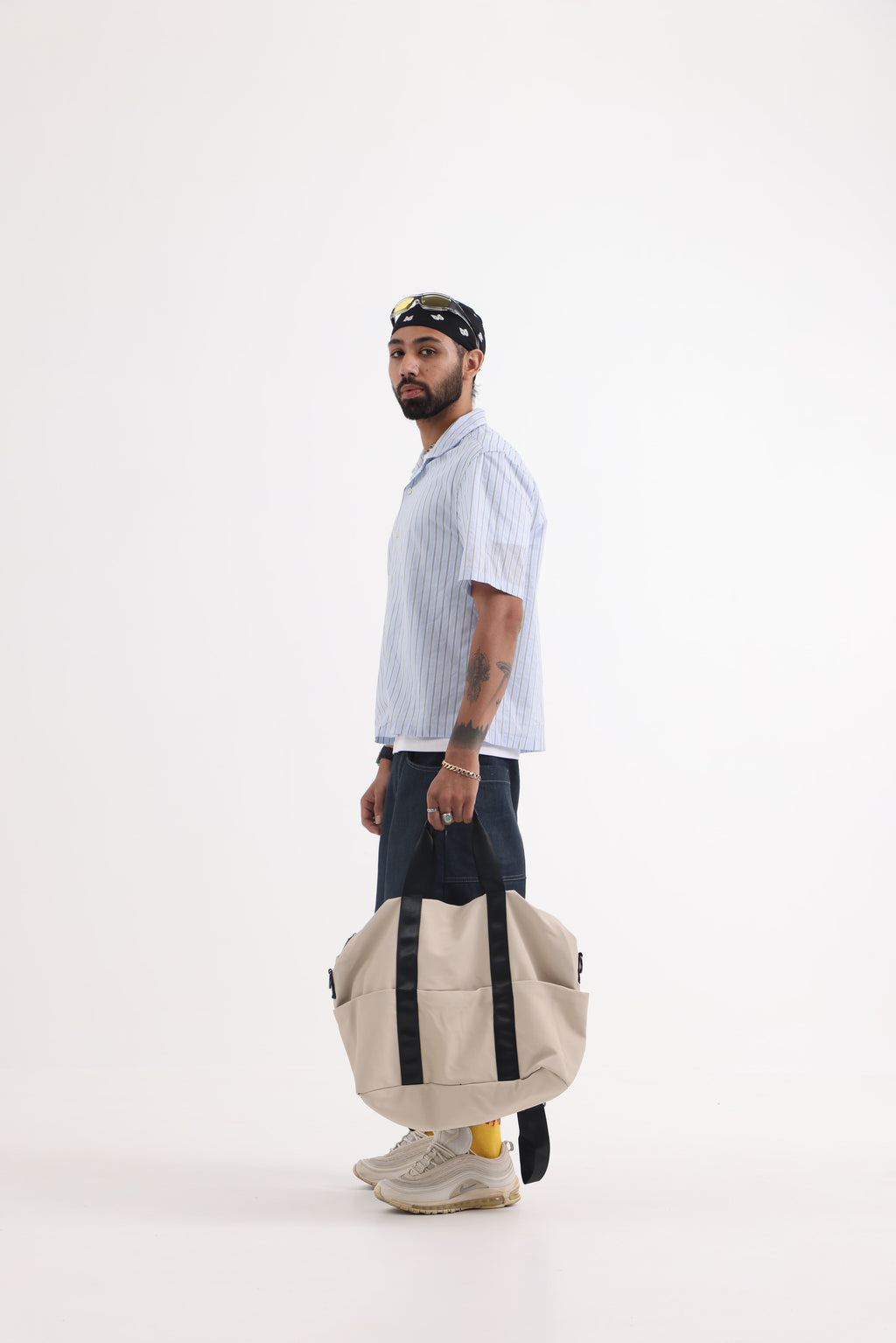 A unisex duffel tote bag with a sleek, minimal design featuring two vertical straps, dual carry handles, an adjustable shoulder strap, and side pockets. Spacious enough for travel or daily use, crafted from durable, water-resistant material with a zippered top closure. Ideal for college, gym, or casual outings.
