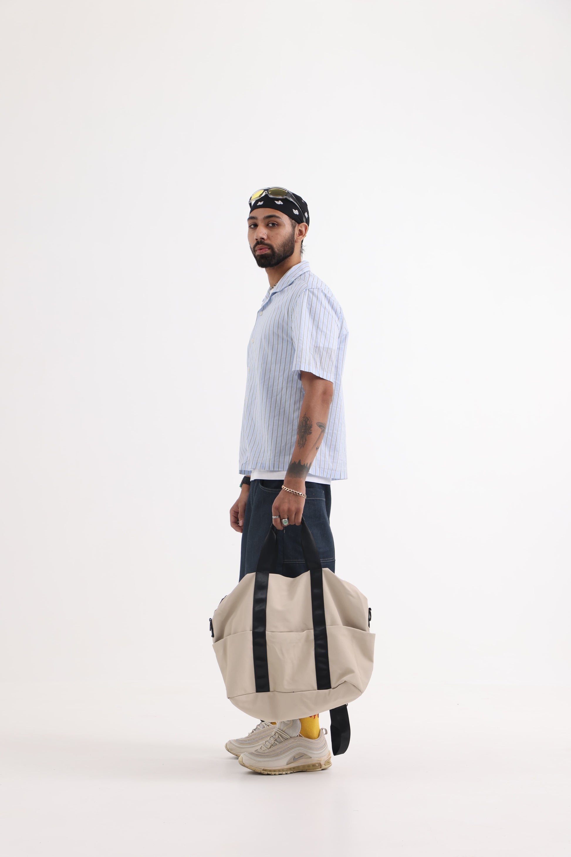 A unisex duffel tote bag with a sleek, minimal design featuring two vertical straps, dual carry handles, an adjustable shoulder strap, and side pockets. Spacious enough for travel or daily use, crafted from durable, water-resistant material with a zippered top closure. Ideal for college, gym, or casual outings.
