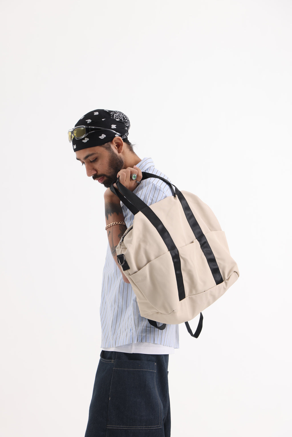 A unisex duffel tote bag with a sleek, minimal design featuring two vertical straps, dual carry handles, an adjustable shoulder strap, and side pockets. Spacious enough for travel or daily use, crafted from durable, water-resistant material with a zippered top closure. Ideal for college, gym, or casual outings.
