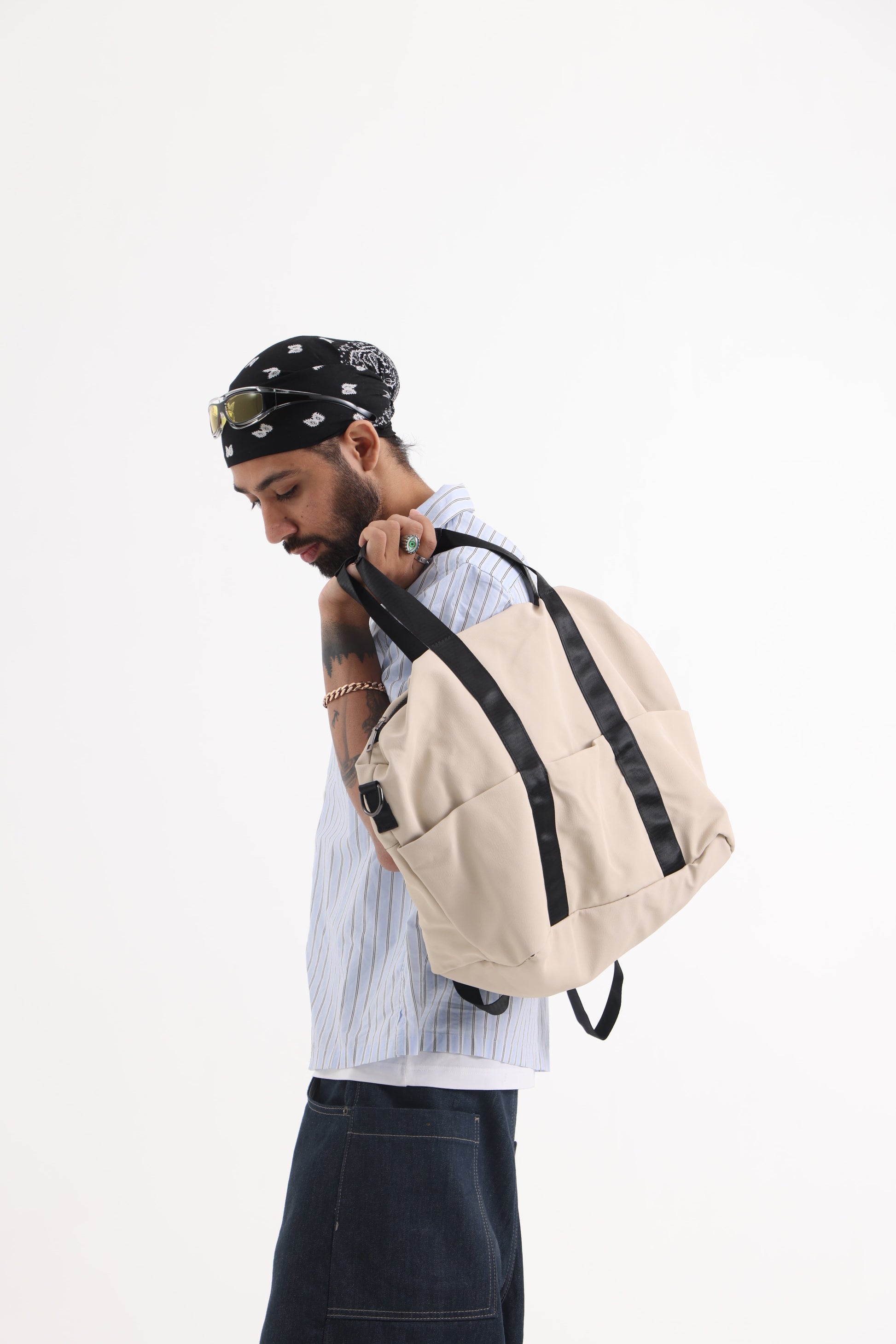 A unisex duffel tote bag with a sleek, minimal design featuring two vertical straps, dual carry handles, an adjustable shoulder strap, and side pockets. Spacious enough for travel or daily use, crafted from durable, water-resistant material with a zippered top closure. Ideal for college, gym, or casual outings.
