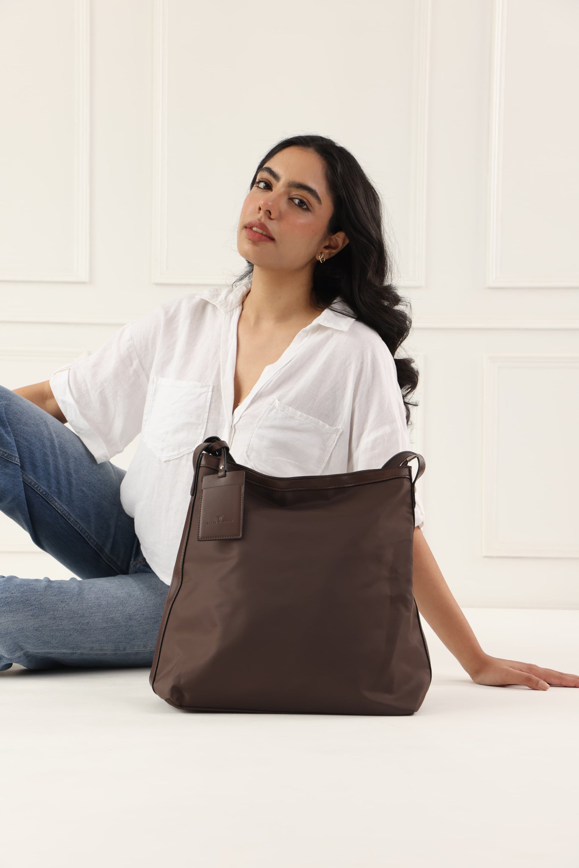 "Minimalist shoulder bag with a structured silhouette, single top strap, and attached tag detail – designed for effortless everyday style. Compact yet spacious enough for daily essentials, perfect for work, brunch, or casual wear. A premium fashion accessory from Tales of Totes, ideal for Indian shoppers seeking elegant, functional handbags beyond standard tote designs."
