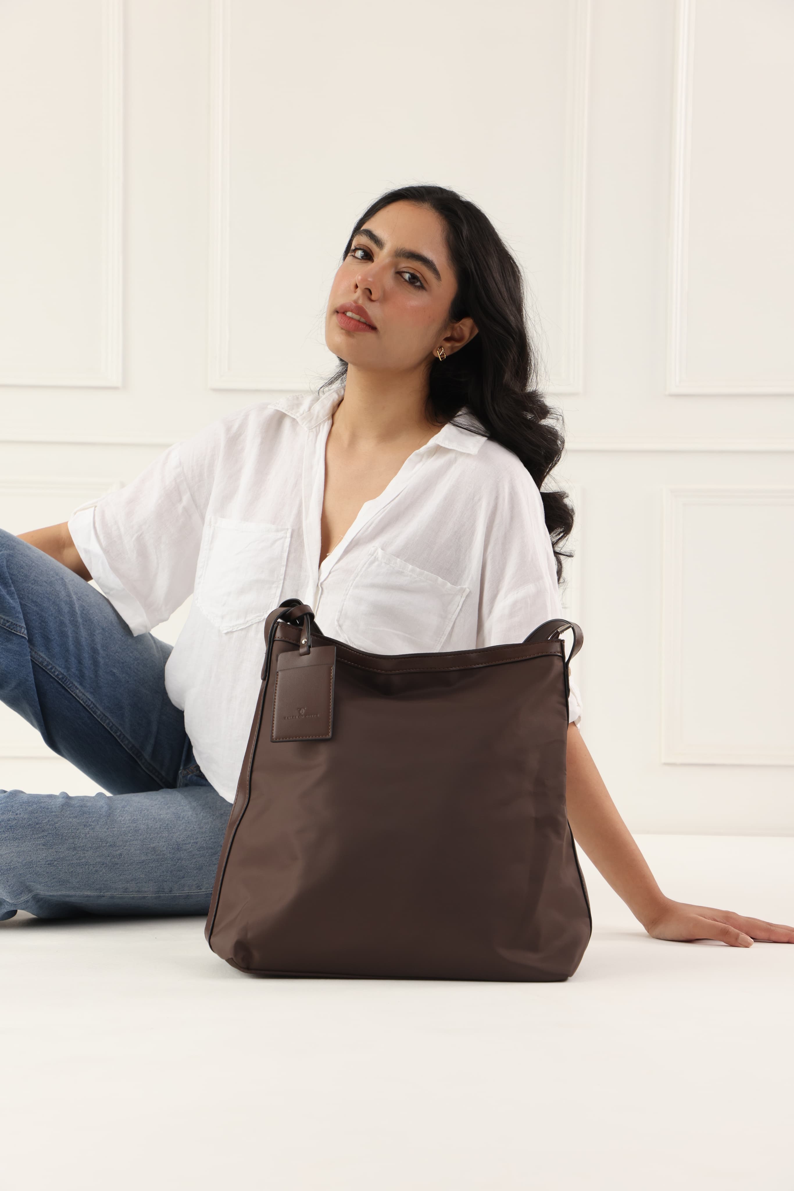 "Minimalist shoulder bag with a structured silhouette, single top strap, and attached tag detail – designed for effortless everyday style. Compact yet spacious enough for daily essentials, perfect for work, brunch, or casual wear. A premium fashion accessory from Tales of Totes, ideal for Indian shoppers seeking elegant, functional handbags beyond standard tote designs."
