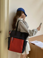 Woman with a black and red bag, wearing a blue cap, standing indoors.