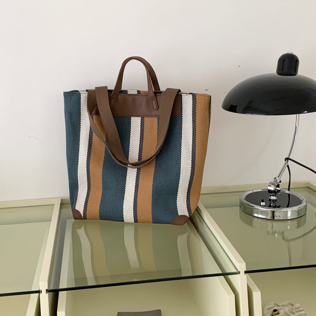 "Eco-friendly striped jute tote bag with dual handles – featuring bold black, grey, and white vertical patterns with leather-look accents and brown straps. Ideal for shopping, office, and casual outings. A sustainable and stylish choice from Tales of Totes – offering earthy, durable fashion accessories that stand apart from brands like Chumbak, Baggit, and DailyObjects in the Indian market."

