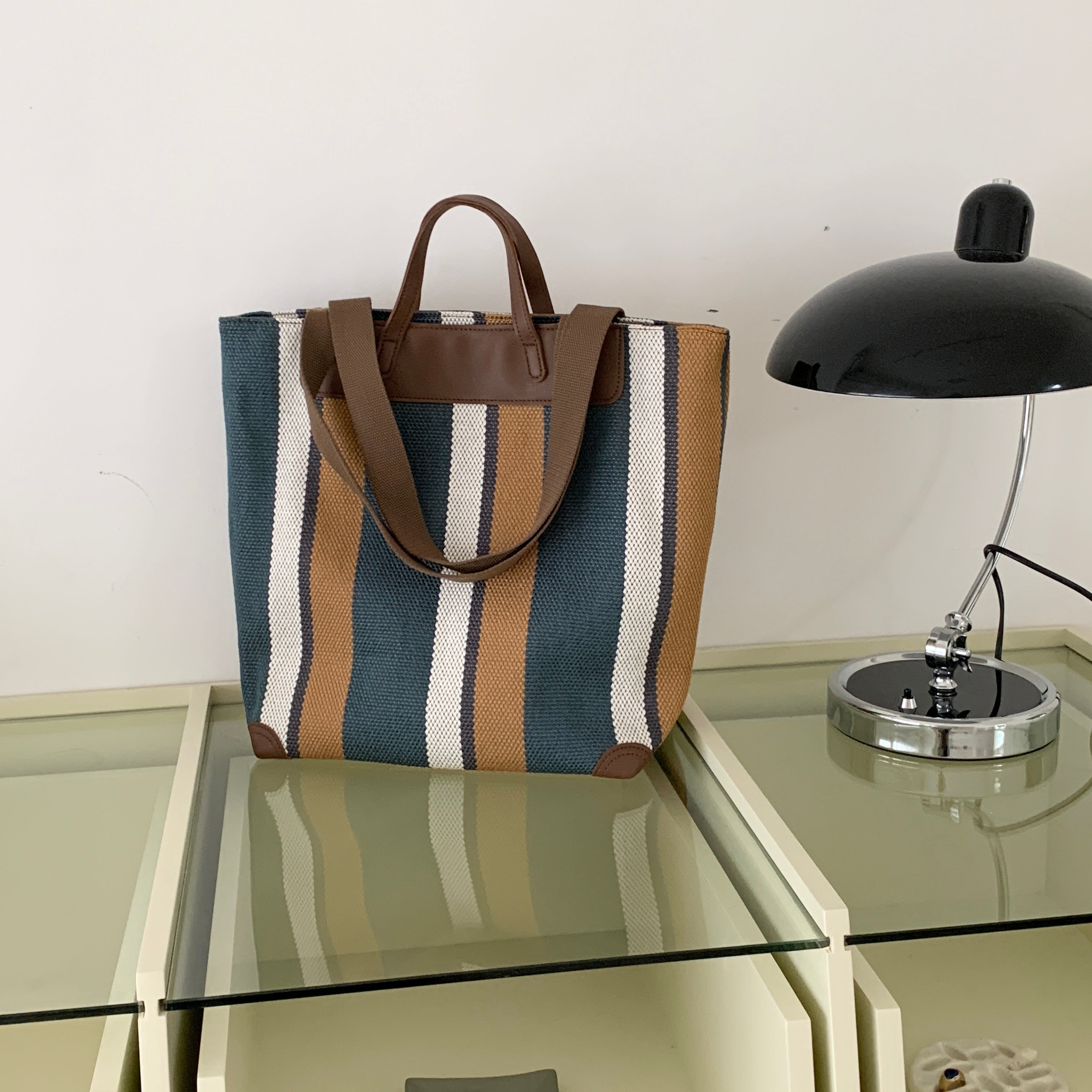 "Eco-friendly striped jute tote bag with dual handles – featuring bold black, grey, and white vertical patterns with leather-look accents and brown straps. Ideal for shopping, office, and casual outings. A sustainable and stylish choice from Tales of Totes – offering earthy, durable fashion accessories that stand apart from brands like Chumbak, Baggit, and DailyObjects in the Indian market."

