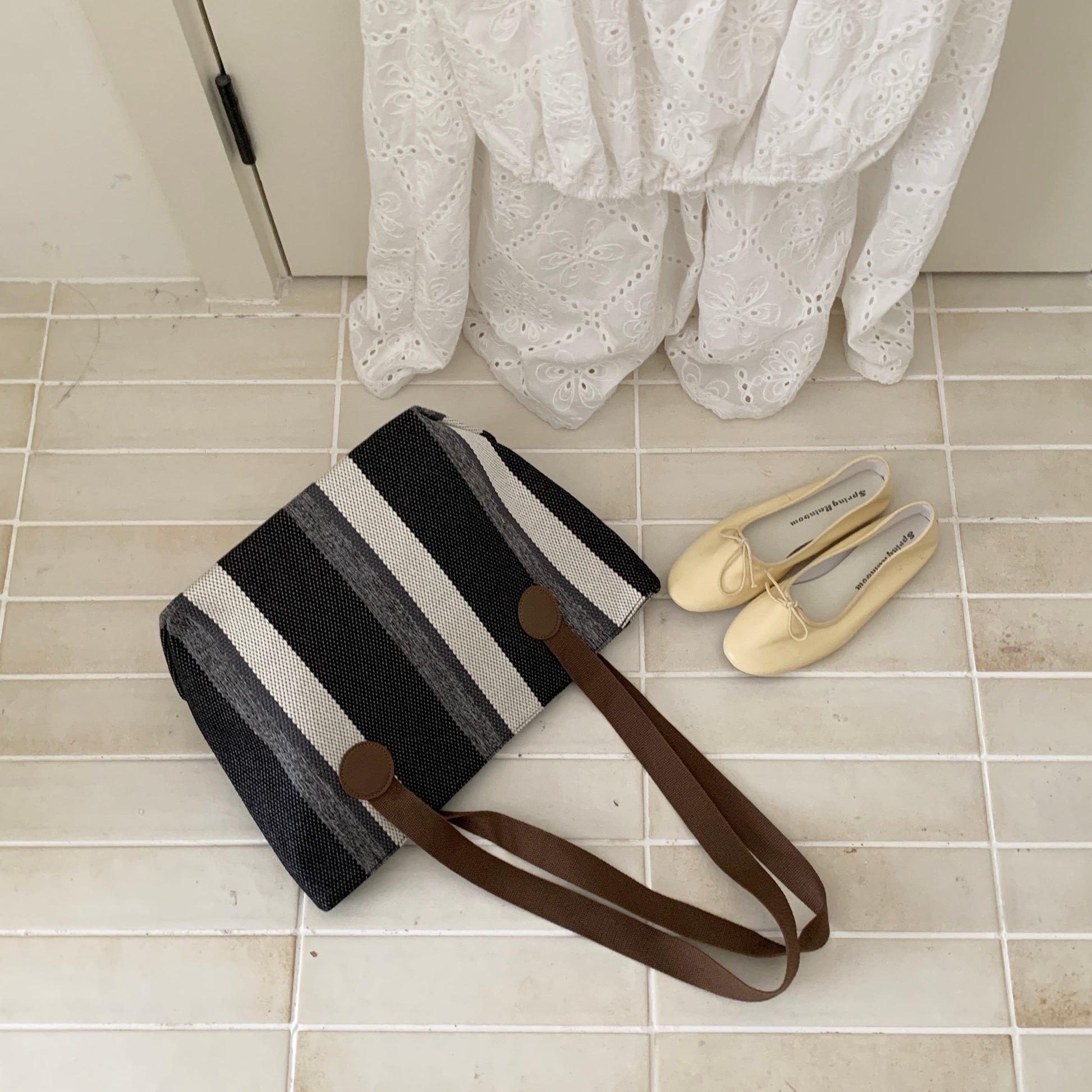 Stylish striped jute tote bag with earthy yellow and beige tones, featuring long brown shoulder straps and circular leather-look accents. Lightweight, eco-conscious, and perfect for daily use, shopping, or office carry. A trendy, sustainable option from Tales of Totes – designed to stand out among Indian tote brands like Chumbak, Baggit, and Zouk."
