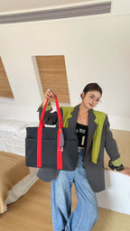 Person holding a black bag with red straps in a bedroom setting