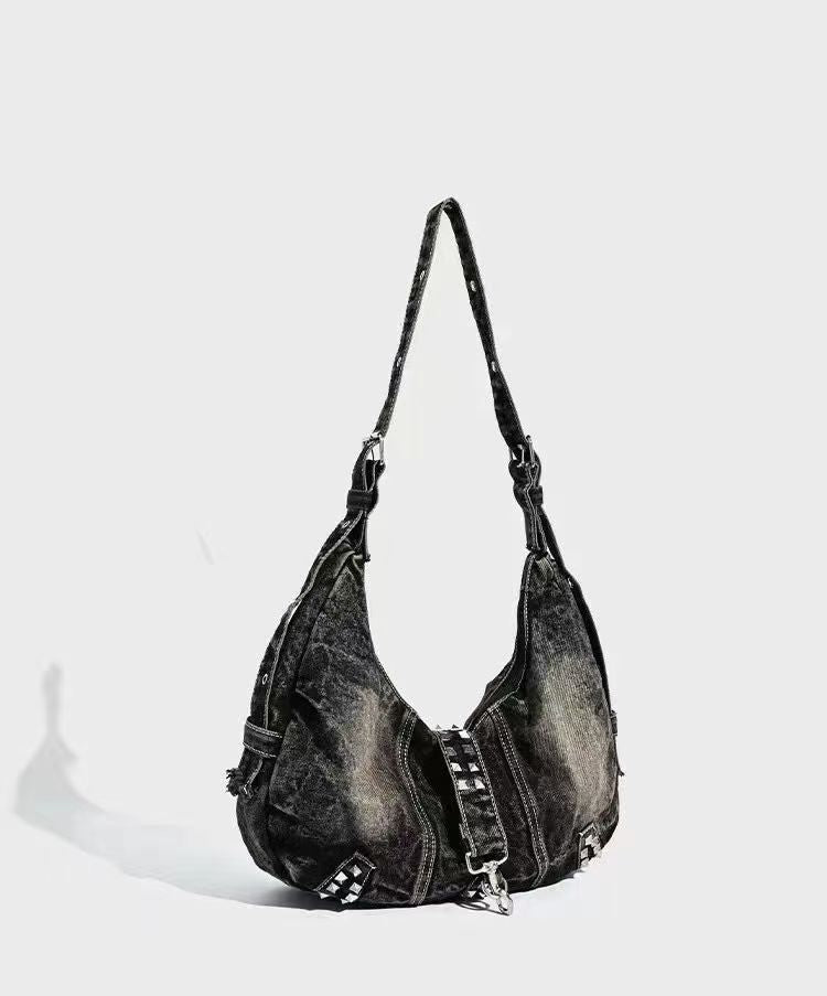 Black denim handbag with studs on a light gray background