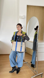 Person holding a tote bag in front of a mirror in a room.