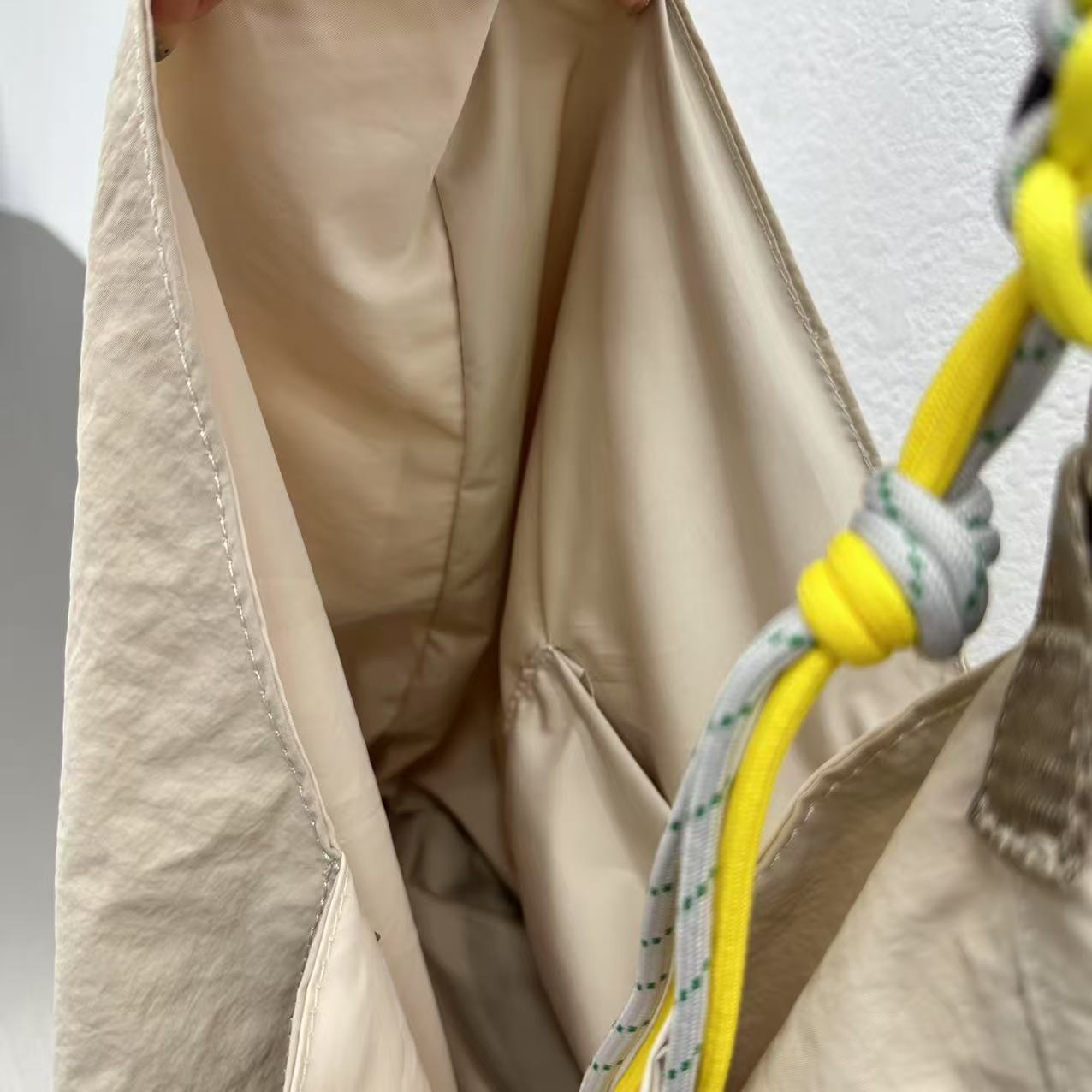 Close-up of beige fabric with a yellow rope tied in a knot. Person holding a gray tote bag in an indoor setting,“Trendy tote bag for women in India with spacious design, inner pocket, and rope handle strap – perfect everyday alternative to Zara tote bags, H&M shopper bags, Mango handbags, Charles & Keith totes, Lifestyle handbags, Myntra handbags, and Fabindia casual totes.”