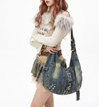 Person holding a denim handbag with studs on a white background
