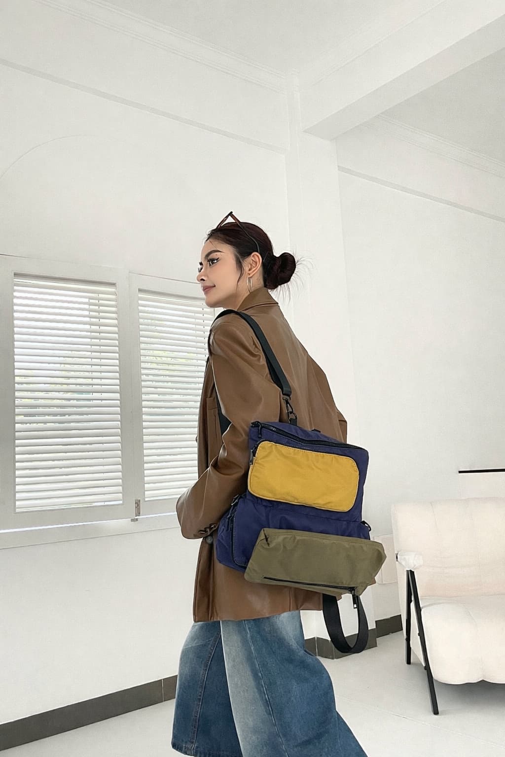 Person wearing a backpack with multiple compartments in a minimalistic room.