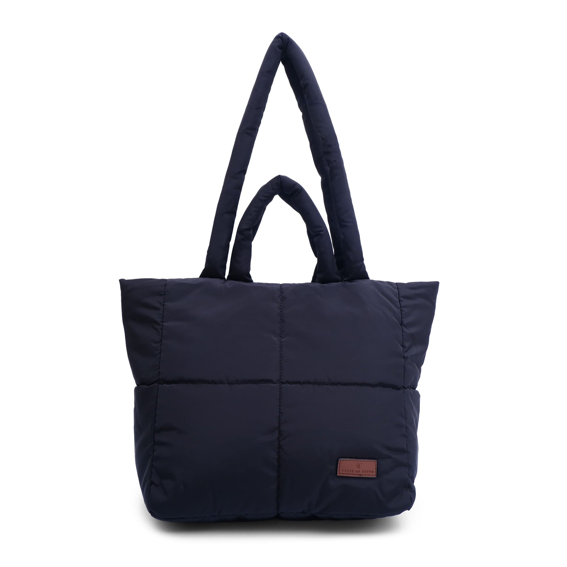 black tote bag with a brown patch on a white background "Minimalist shoulder bag with a structured silhouette, single top strap, and attached tag detail – designed for effortless everyday style. Compact yet spacious enough for daily essentials, perfect for work, brunch, or casual wear. A premium fashion accessory from Tales of Totes, ideal for Indian shoppers seeking elegant, functional handbags beyond standard tote designs."
