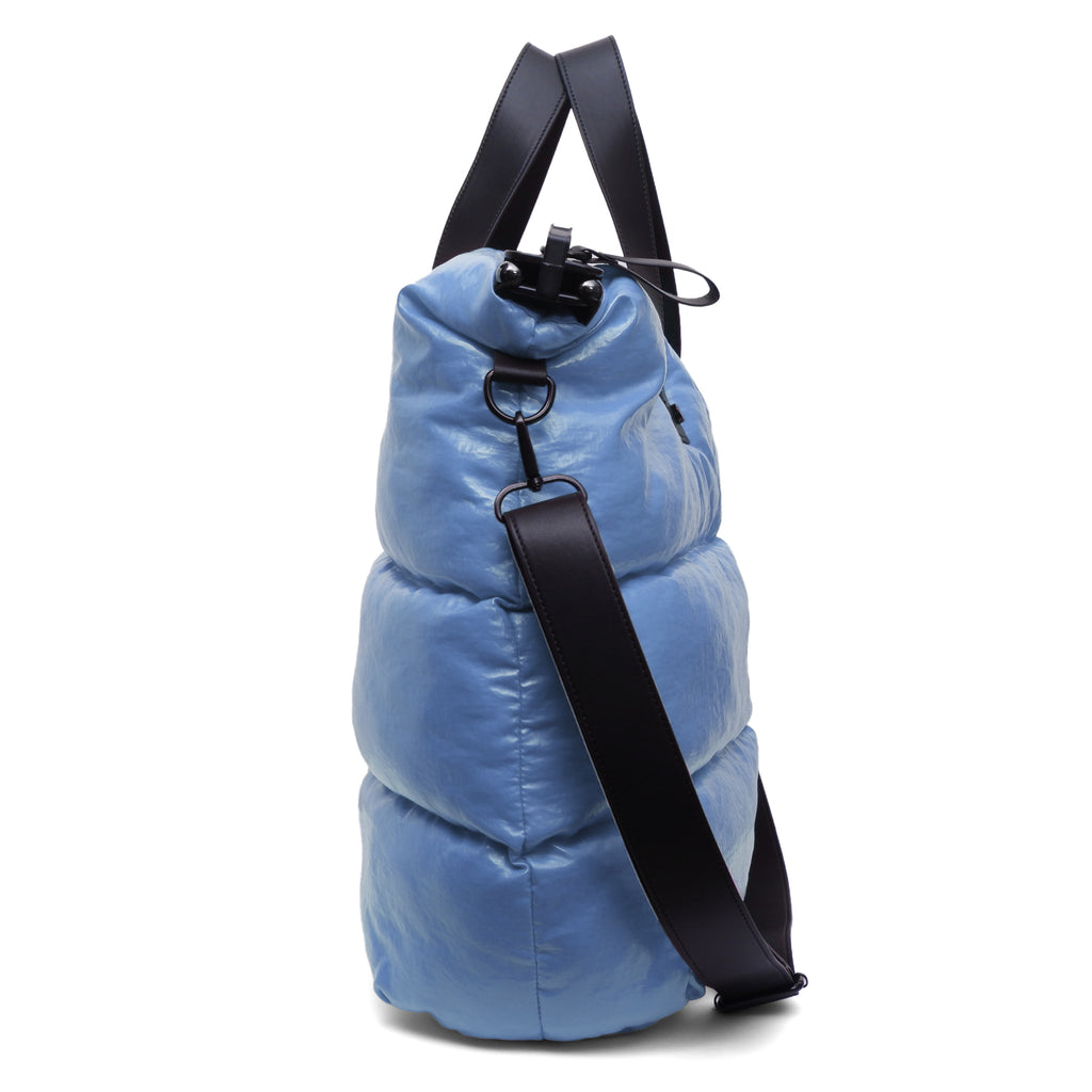 Blue puffer bag with a black strap on a white background