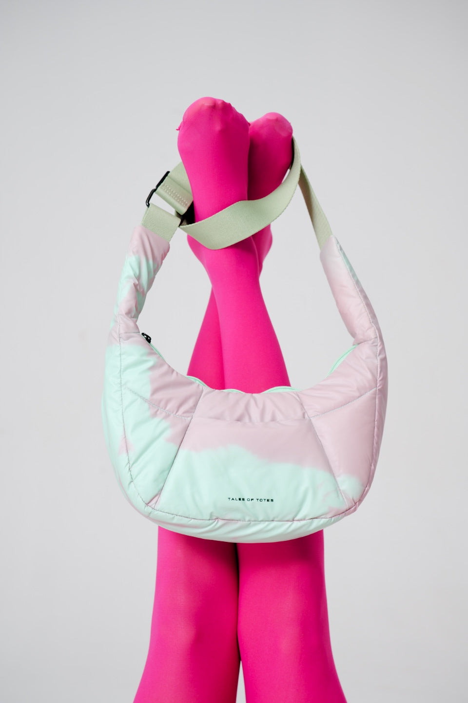 Pink mannequin wearing a quilted pink and light blue handbag against a gray background