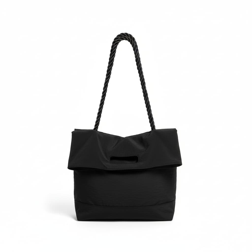Black handbag with a rope handle on a white background,High-quality red tote bag for women and girls from a new Indian fashion brand. Features a unique top-fold flap design and sturdy braided black rope handles. Perfect for carrying laptops and essentials, making it a stylish and functional bag for office, college, or casual outings in India. A chic and trending design for the modern Indian woman, available online with free shipping.