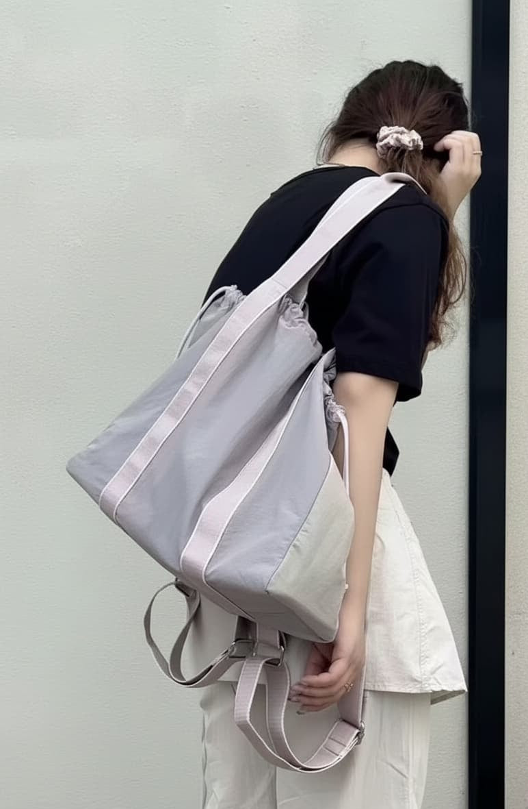 Person wearing a gray and white backpack against a plain background,A versatile and stylish tote bag for women, perfect for the Indian market, shot from a side angle showing the product in use. The bag is made from a durable, high-quality fabric and features a casual, comfortable design with shoulder straps. This fashion accessory is ideal for a daily commute, college, or casual outings. It's a must-have for those seeking a practical yet trendy handbag in India.