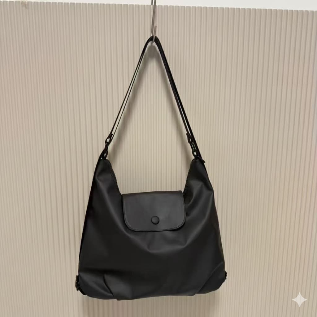 Black handbag hanging on a beige textured wall,laptop tote bag for women, tote bag for office use, college tote bag with zipper, and stylish bags for girls. You can also target users with specific needs by using long-tail phrases like vegan leather tote bag or tote bag for daily use in India. To understand the market better, keep an eye on competitors such as Lavie, Baggit, and Caprese, all of which are major players in the Indian handbag space, along with brands like Zouk and Hidesign that cater to specifi