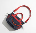 Navy and red handbag with a coiled orange rope on a light gray background