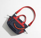 Navy and red handbag with a coiled orange rope on a light gray background