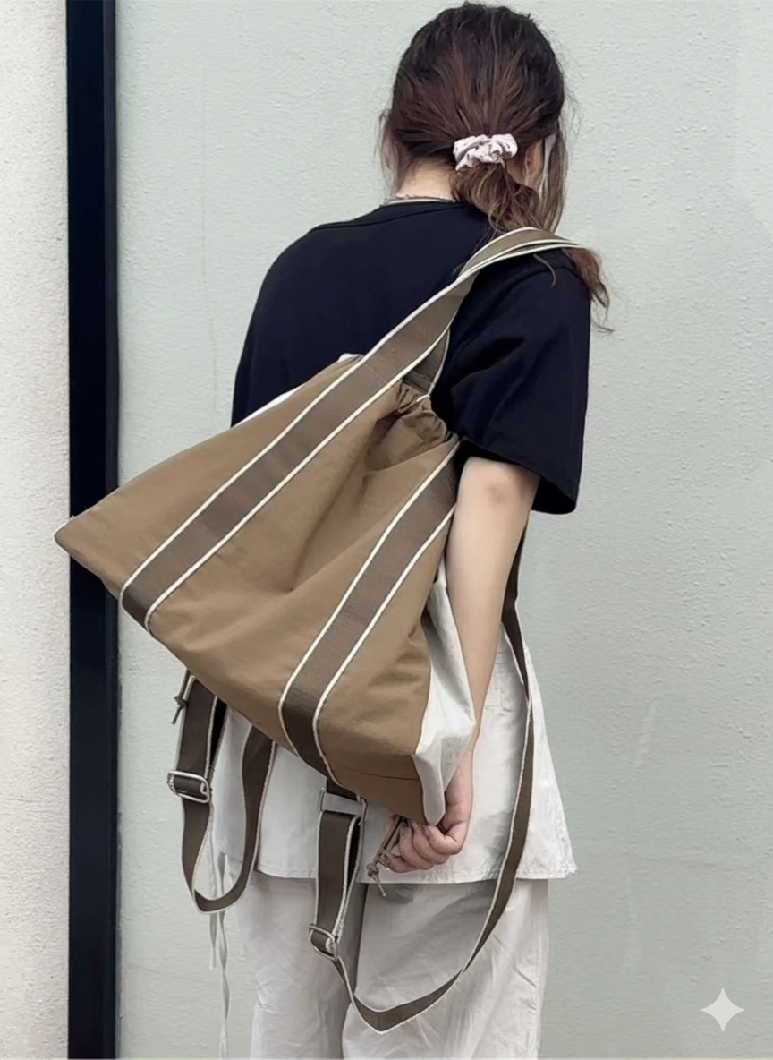 Person holding a large brown bag against a plain background,A versatile and stylish tote bag for women, perfect for the Indian market, shot from a side angle showing the product in use. The bag is made from a durable, high-quality fabric and features a casual, comfortable design with shoulder straps. This fashion accessory is ideal for a daily commute, college, or casual outings. It's a must-have for those seeking a practical yet trendy handbag in India.