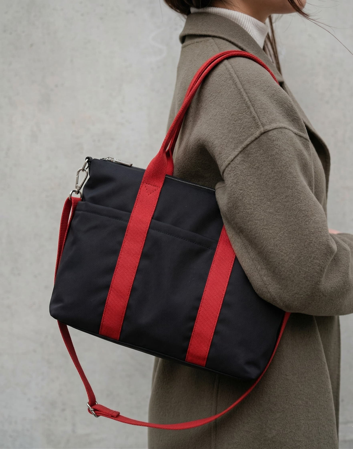 Person wearing a black bag with red straps against a neutral background