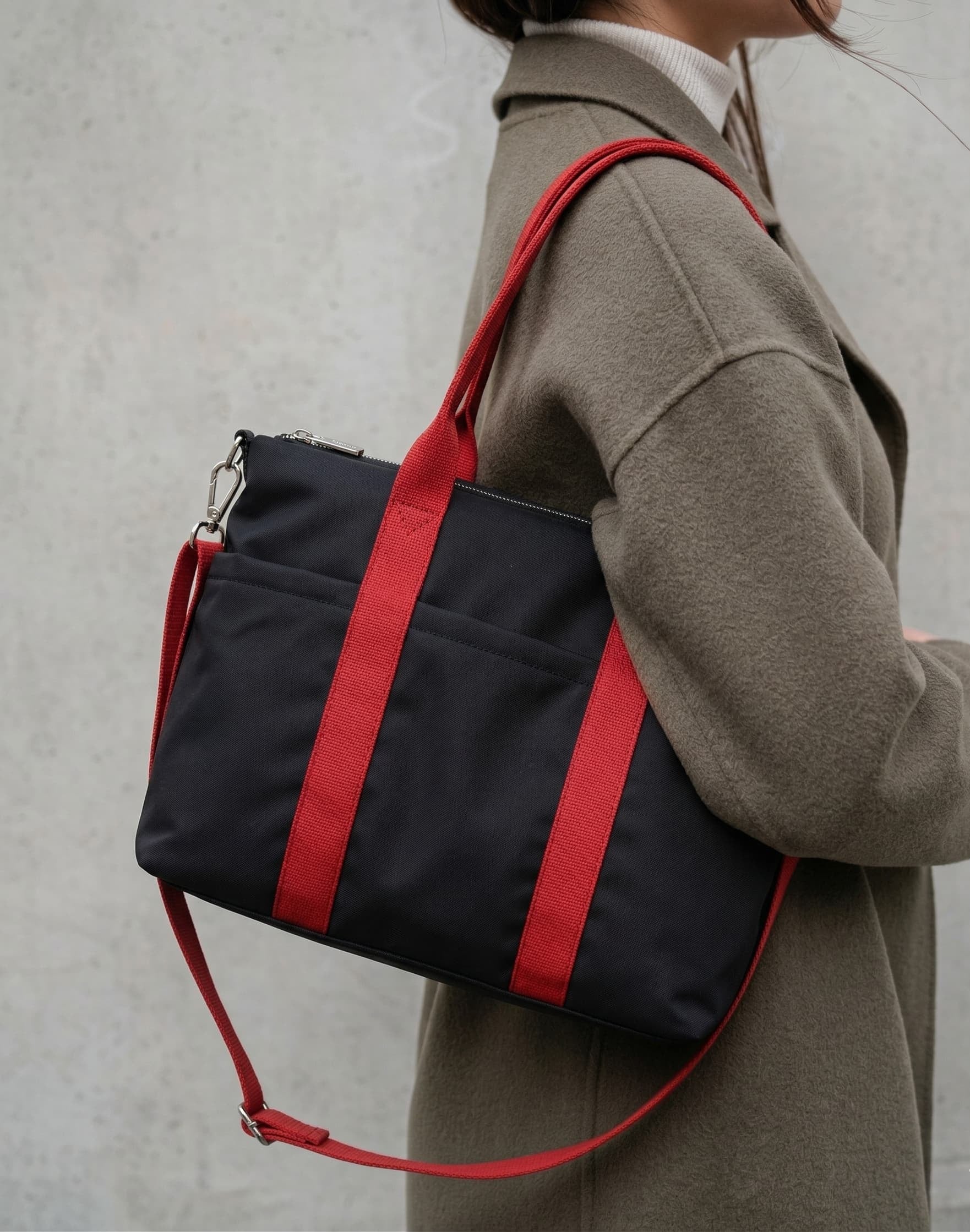 Person wearing a black bag with red straps against a neutral background