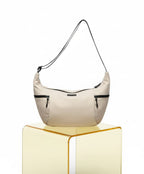 Beige handbag with black accents on a transparent yellow stand against a white background