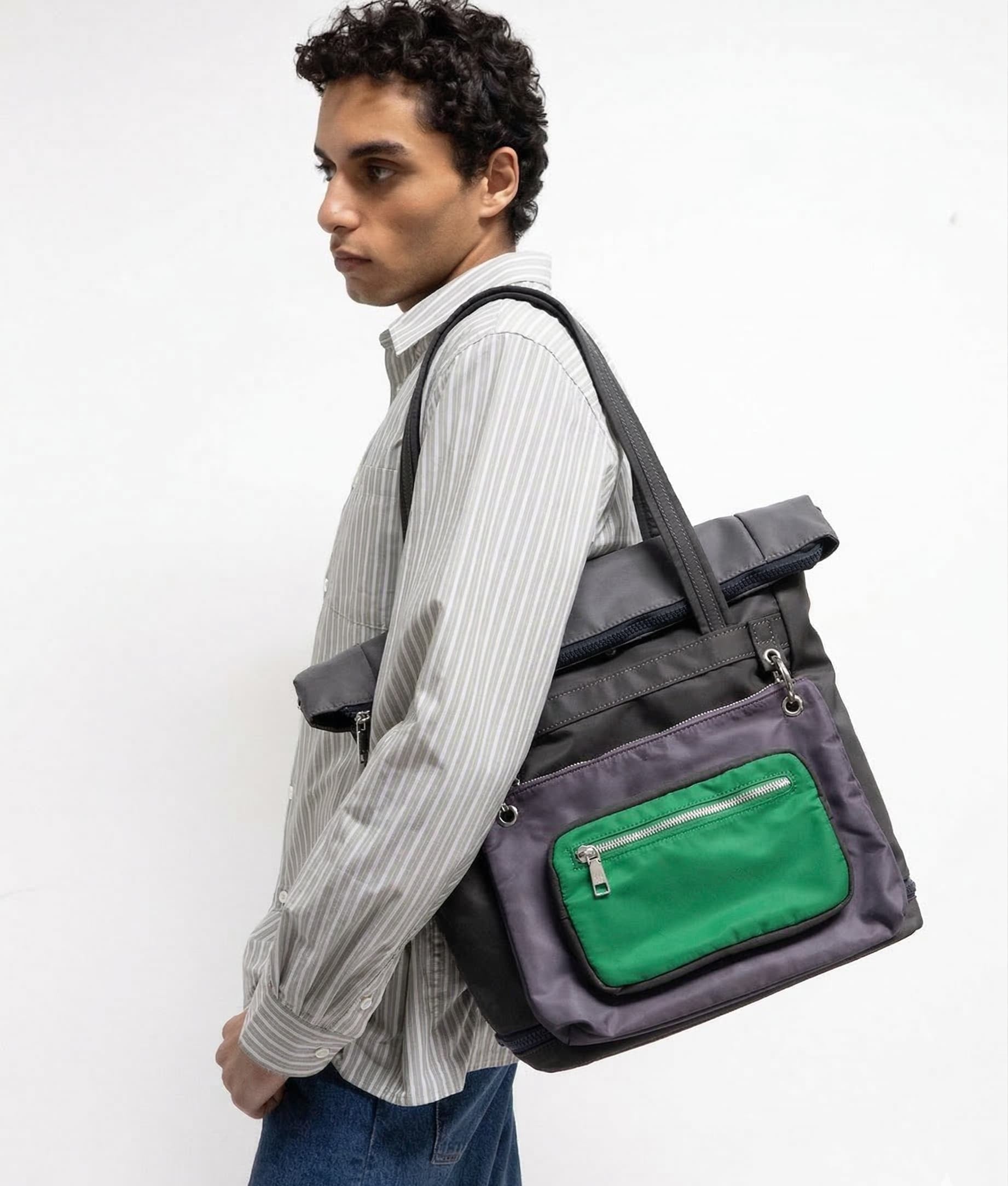 Man carrying a gray backpack with a green pocket on a white background