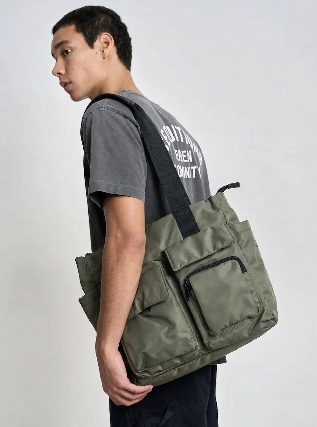 Person wearing a green bag over one shoulder on a plain background