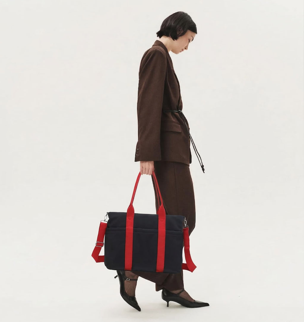 Person holding a black and red bag on a white background