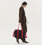 Person holding a black and red bag on a white background