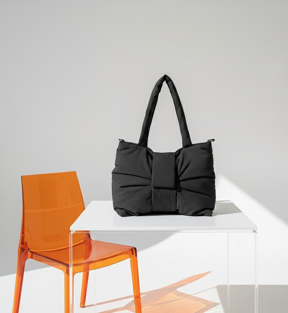 Black handbag on a white table with an orange chair against a gray background"High-fashion tote bag made for India’s trendsetters – featuring a sleek design, premium nylon finish, and waterproof build. A perfect fusion of functionality and streetwear style for Gen Z and millennial shoppers. Stand out from the crowd with Tales of Totes – India’s rising alternative to DailyObjects, Zouk, Chumbak, and Miraggio. Ideal for styling with casual, college, or office looks."
