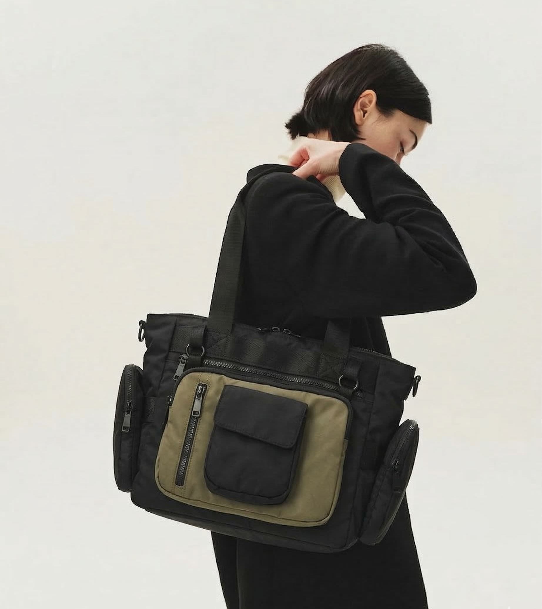 Person wearing a black and green bag on a plain background