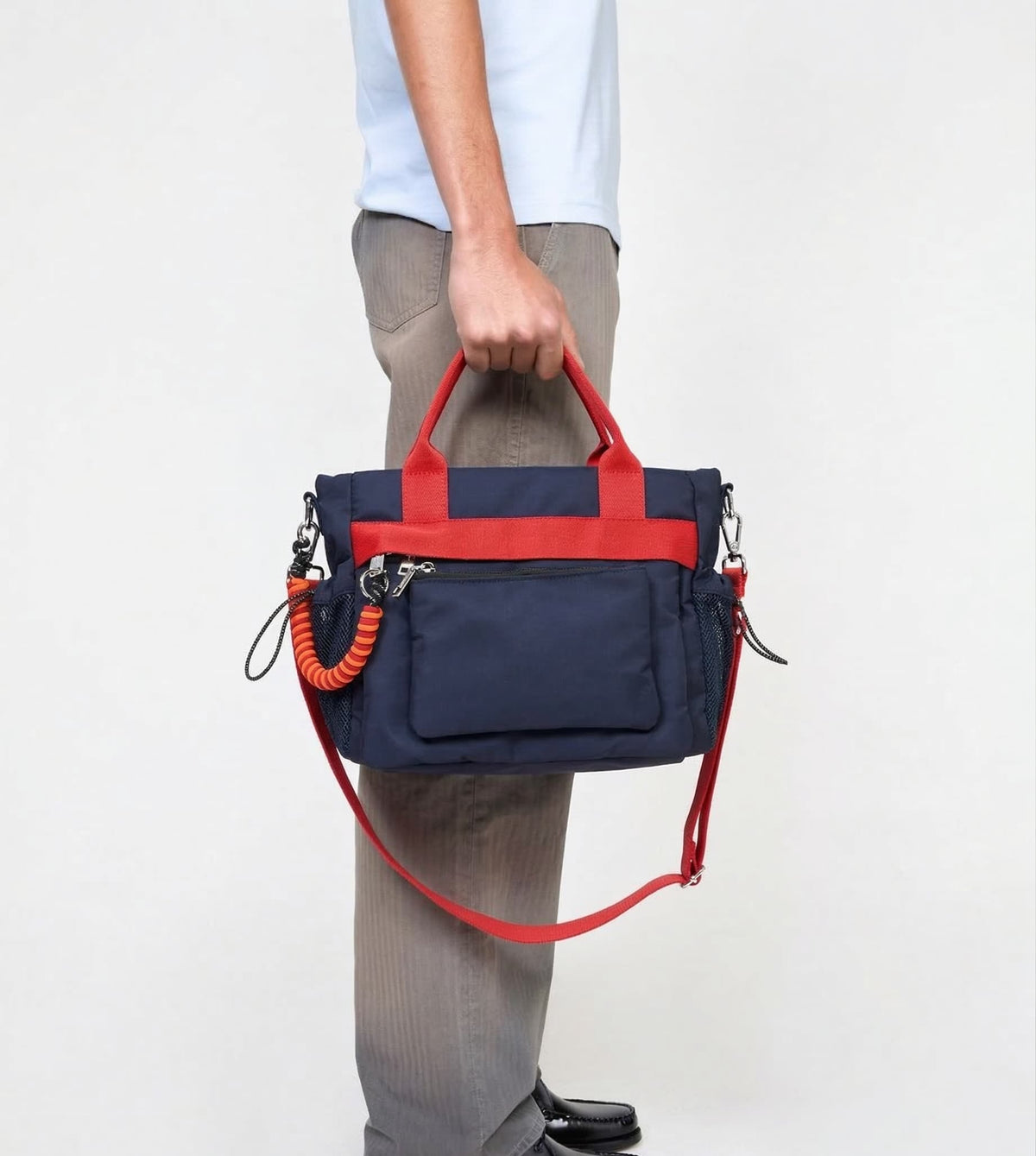 Navy and red handbag held by a person on a white background