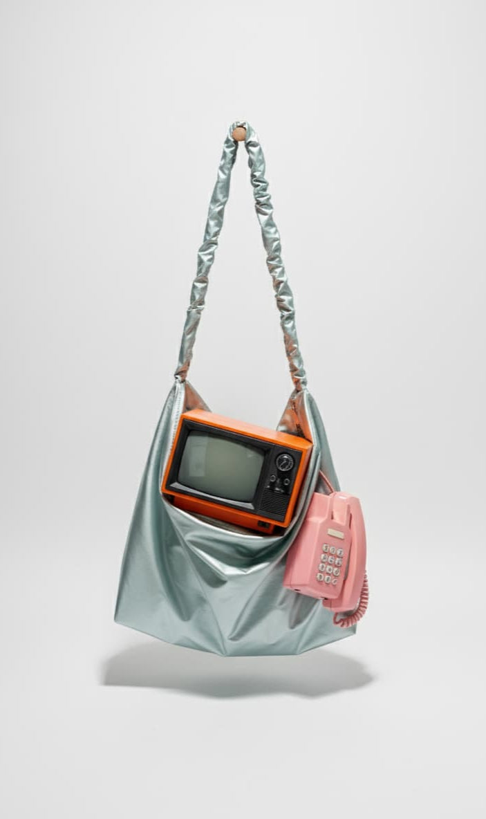 Light blue handbag with a vintage orange camera and pink phone on a white background
