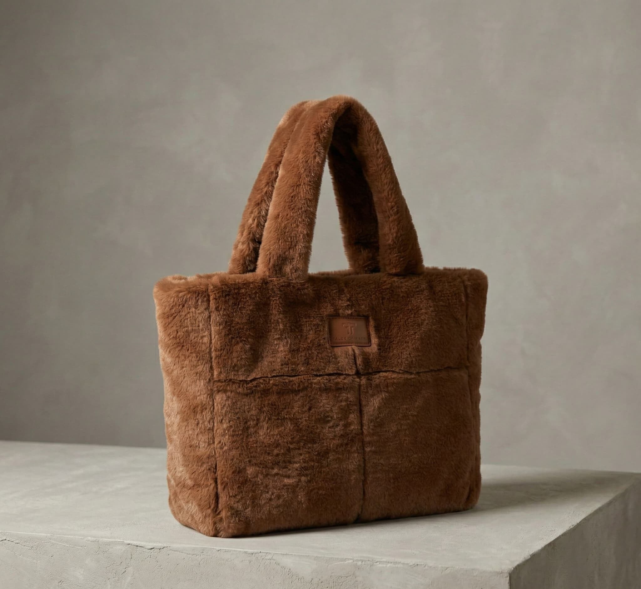 Brown fluffy tote bag on a concrete surface with a neutral background