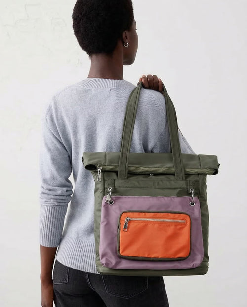 Person wearing a green and orange backpack on a plain background