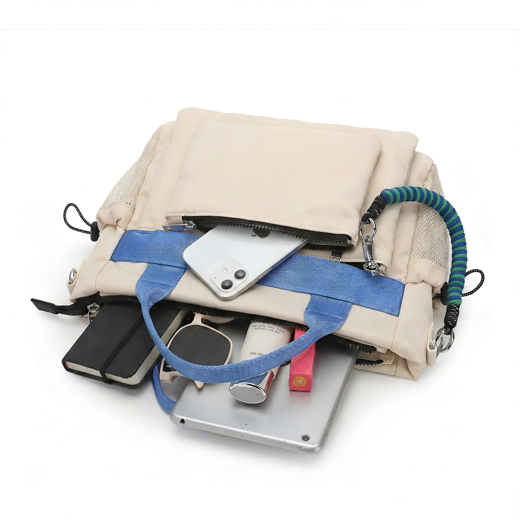 Open beige handbag with blue strap containing various items on a white background