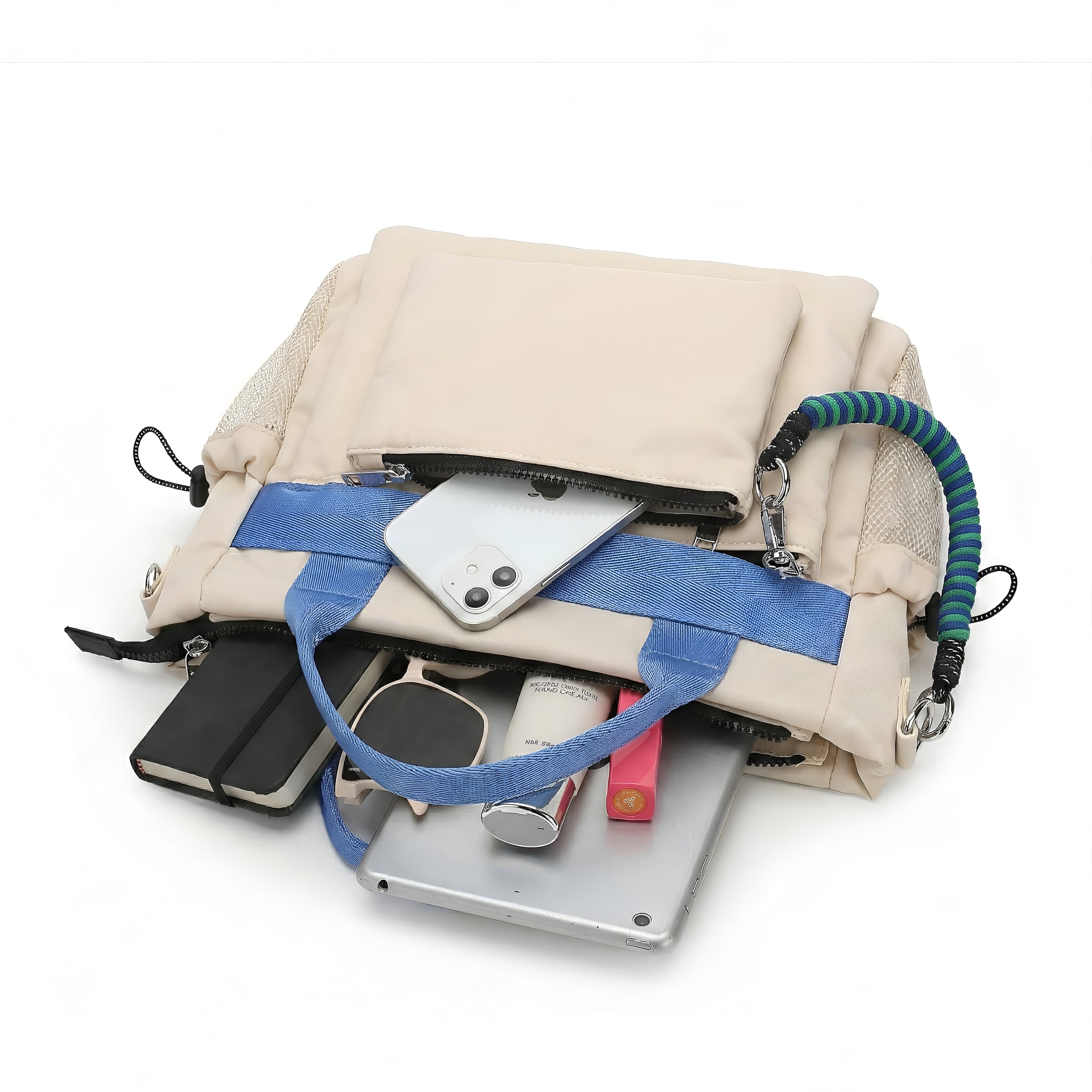 Open beige handbag with blue strap containing various items on a white background