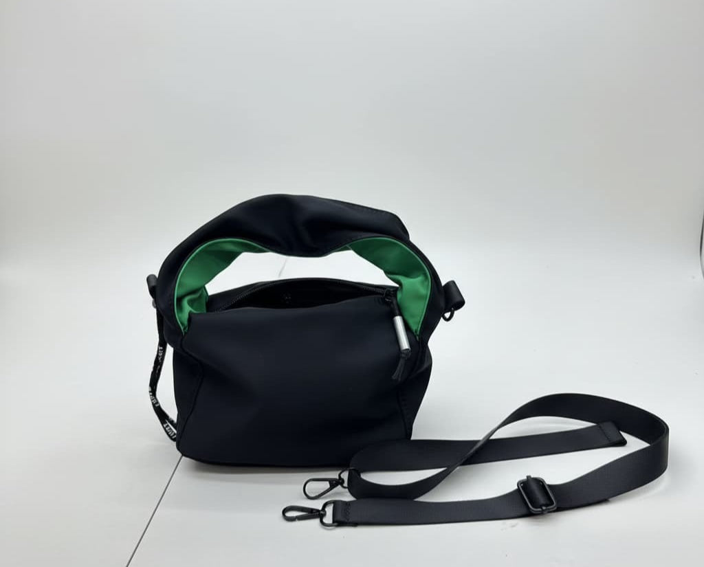 Black bag with green interior on a white background"Black waterproof polyester mini tote bag with stylish green lining, lightweight and durable design, adjustable crossbody strap and spacious compartments for wallet, phone, cosmetics and daily essentials. Perfect handbag for women in India for office, college, travel, shopping, and everyday use. Premium quality ladies tote bag available online at best price in India, versatile small carry bag for students, professionals, and travelers."