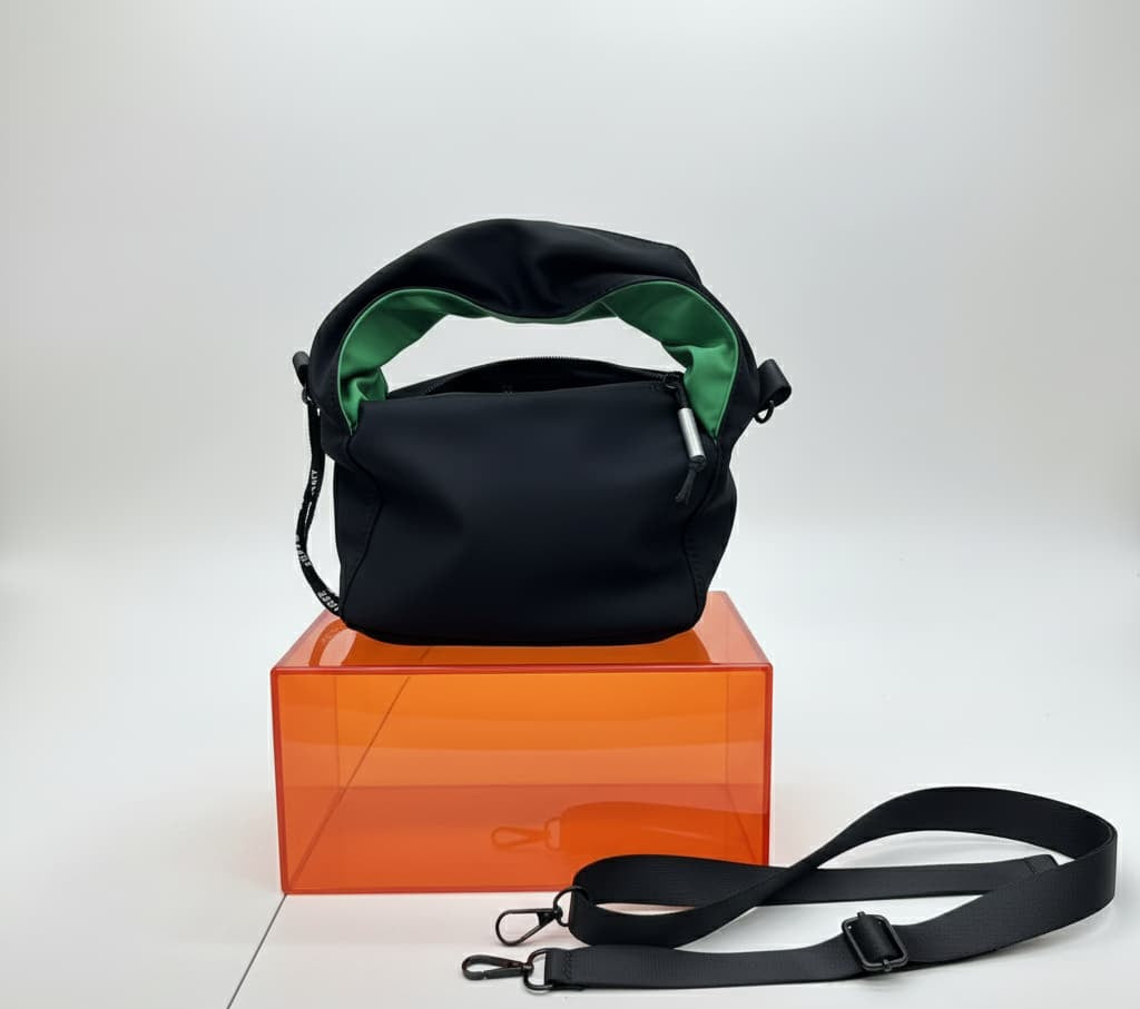 Black handbag with green interior on an orange box against a white background,"Black waterproof polyester mini tote bag with stylish green lining, lightweight and durable design, adjustable crossbody strap and spacious compartments for wallet, phone, cosmetics and daily essentials. Perfect handbag for women in India for office, college, travel, shopping, and everyday use. Premium quality ladies tote bag available online at best price in India, versatile small carry bag for students, professionals, and trave