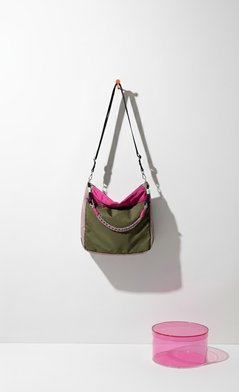 Green and pink bag with a pink cylindrical object on a white background