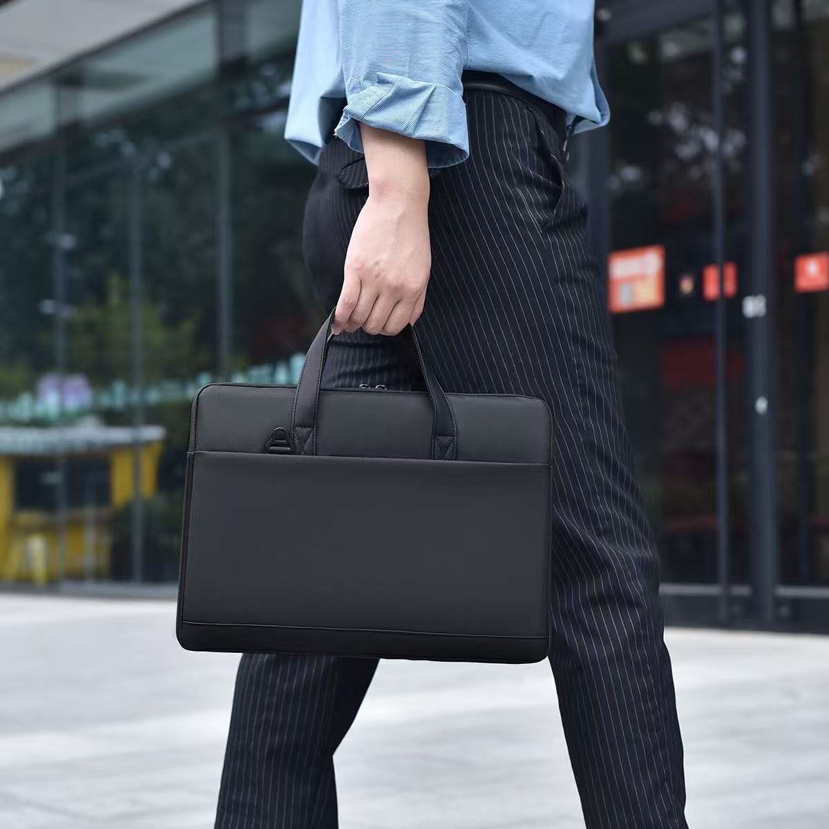 Person holding a black briefcase in an urban setting Black laptop office tote bag for men and women by Tales of Tote, premium faux leather formal bag designed for Indian professionals — sleek, minimalist, lightweight, padded laptop compartment, ideal for work, meetings, hybrid jobs, gifting, and daily commute. Stylish work tote with zipper closure, dual handles, and waterproof finish. Unisex corporate tote for executives, startup founders, students, and remote workers. Best office bag India 2025. Perfect fo
