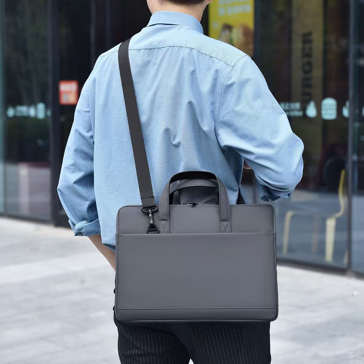 Person wearing a gray shoulder bag on an urban street Black laptop office tote bag for men and women by Tales of Tote, premium faux leather formal bag designed for Indian professionals — sleek, minimalist, lightweight, padded laptop compartment, ideal for work, meetings, hybrid jobs, gifting, and daily commute. Stylish work tote with zipper closure, dual handles, and waterproof finish. Unisex corporate tote for executives, startup founders, students, and remote workers. Best office bag India 2025. Perfect f