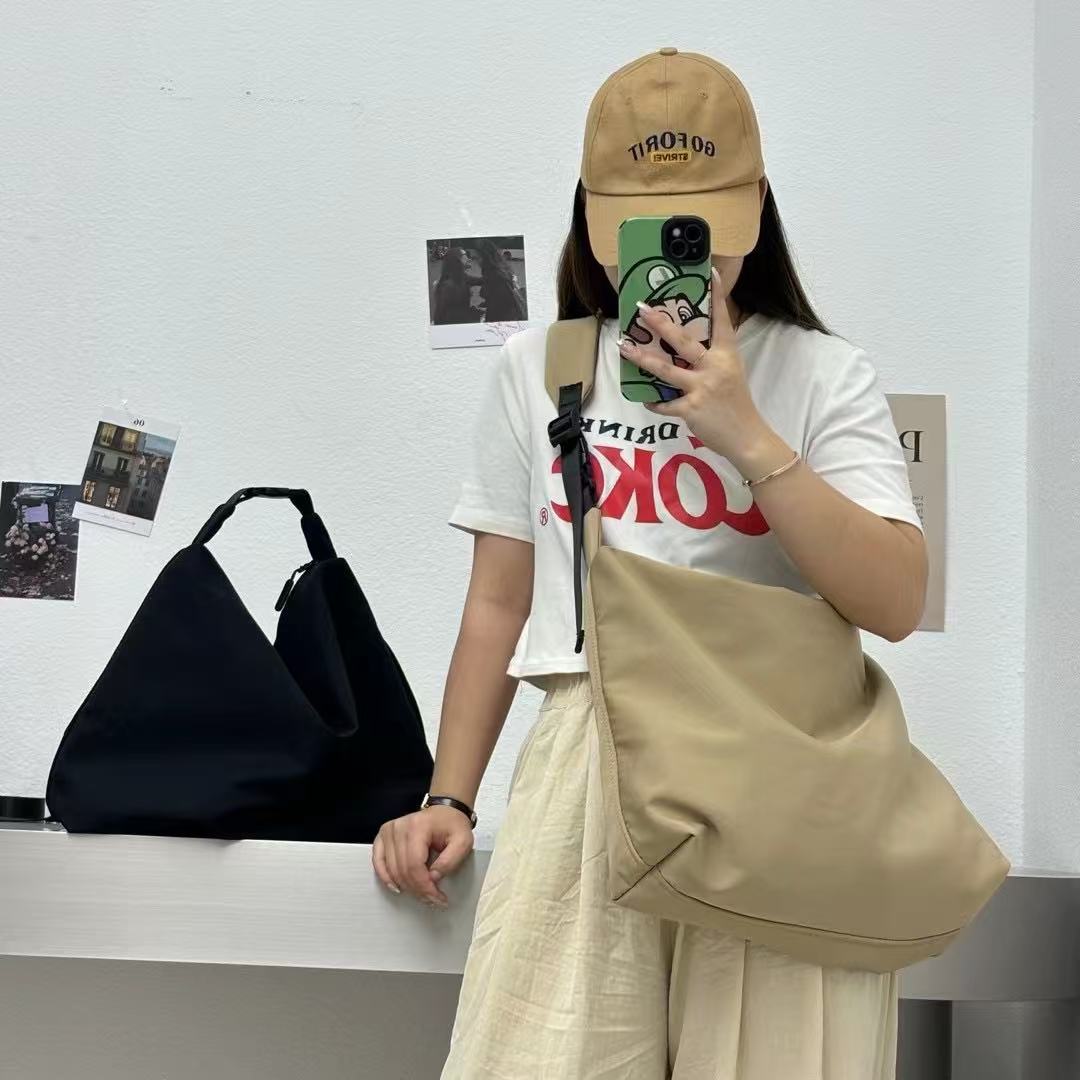 Person holding a beige bag with a white wall and black bag in the background,Convertible nylon tote bag with detachable crossbody strap, zippered front pocket, and main compartment. Available in olive green, black, and beige.

Option 2 (Feature-Focused): Adjustable sl
