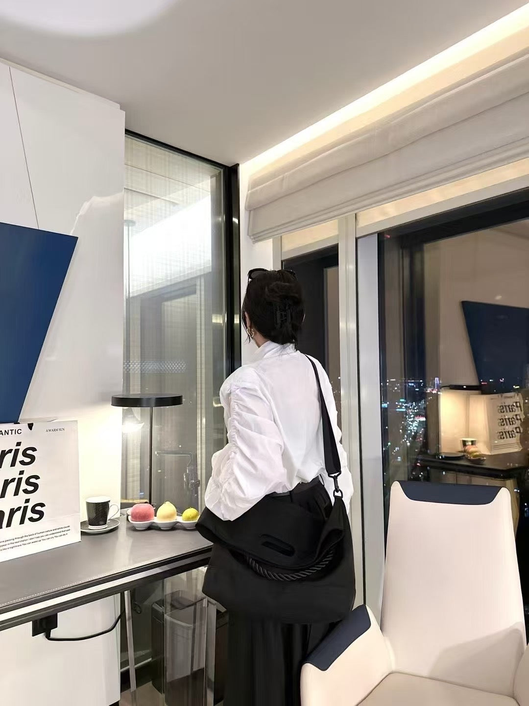 Person sitting at a desk in a modern office setting with 'paris' posters.Black handbag with a rope handle held by a person on a white surface.,High-quality red tote bag for women and girls from a new Indian fashion brand. Features a unique top-fold flap design and sturdy braided black rope handles. Perfect for carrying laptops and essentials, making it a stylish and functional bag for office, college, or casual outings in India. A chic and trending design for the modern Indian woman, available online with f